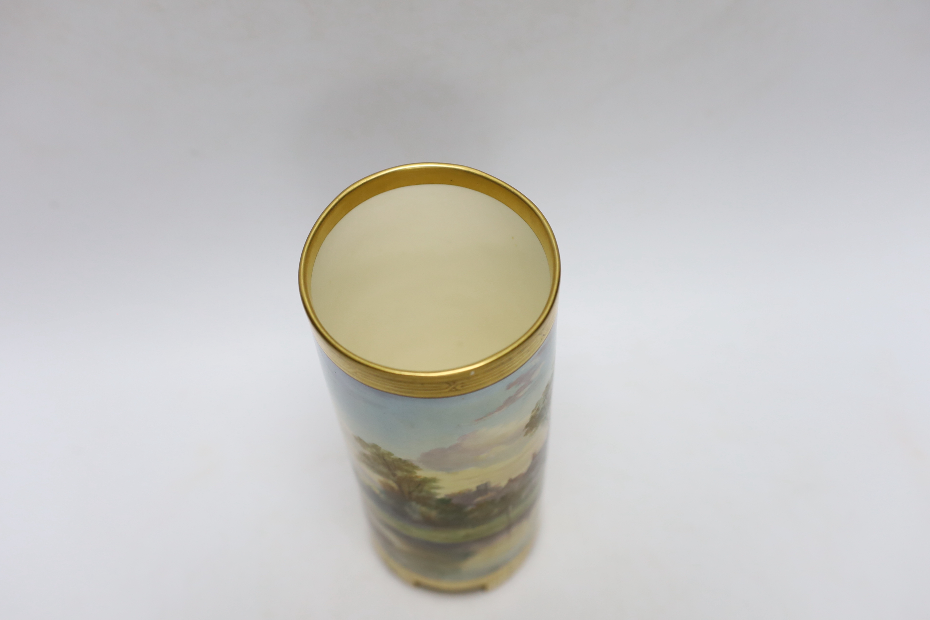 A Mintons porcelain cylinder vase, c.1880, painted with figures along a lakeside path with cottages, 20cm high